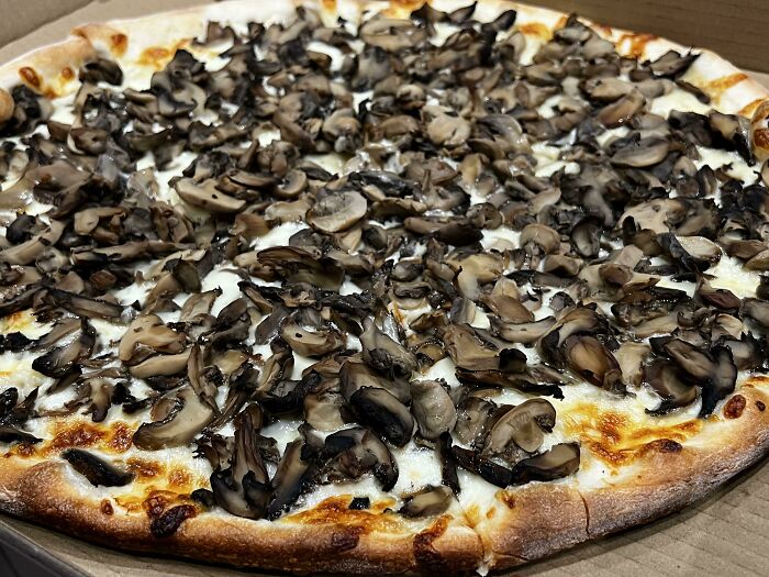 Pizza grande con queso y champiñones frescos, ideal para personas que pidieron algo y se alegraron mucho al recibirlo.