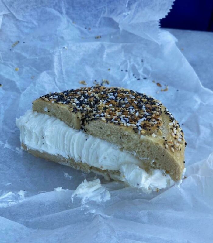 Bagel con queso crema, persona feliz al recibir exactamente lo pedido, momento de alegría y satisfacción en comida.
