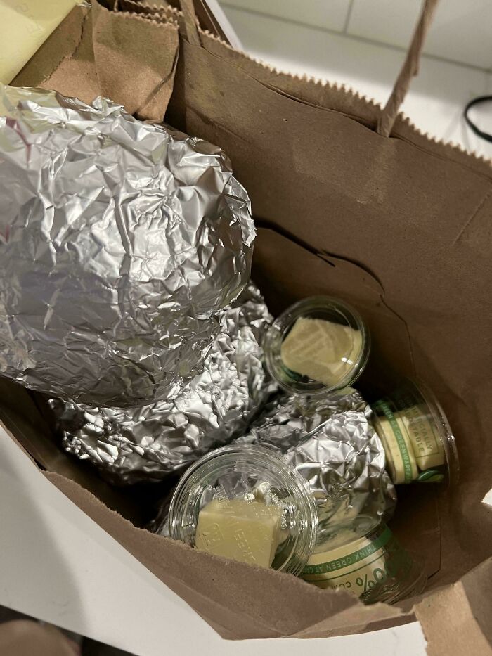 Bolsas con comida envuelta en papel aluminio y salsas en envases pequeños, personas que pidieron algo y se alegraron.