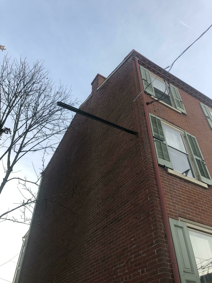 Este poste de una señal quedó encajado a este lado de mi apartamento después de un accidente de un conductor ebrio en mi calle