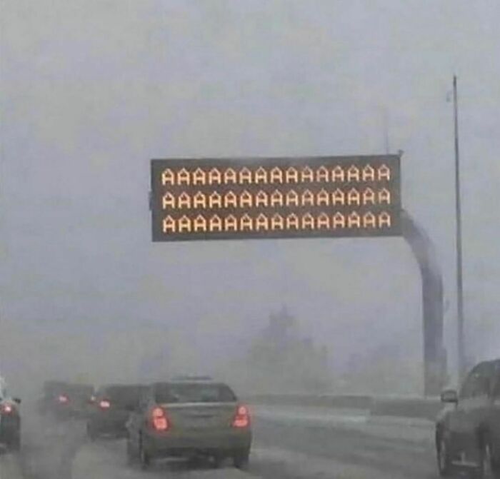 Señal de tráfico en carretera con mensaje repetido de letras A, imagen incómoda y divertida sobre situaciones cotidianas.