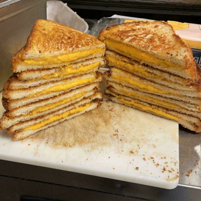 Sándwiches de queso a la parrilla apilados, mostrando capas perfectamente tostadas y queso derretido, alegría al recibirlo.