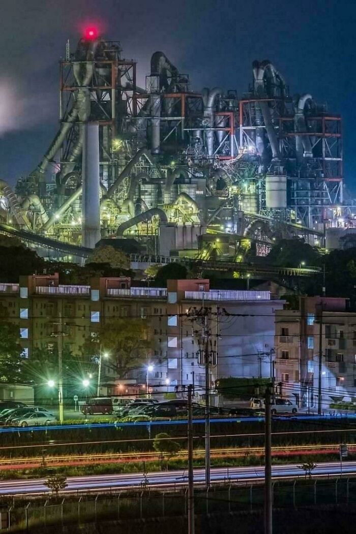 Planta industrial extremadamente grande iluminada de noche, mostrando lo impresionante y aterrador de objetos de gran tamaño.