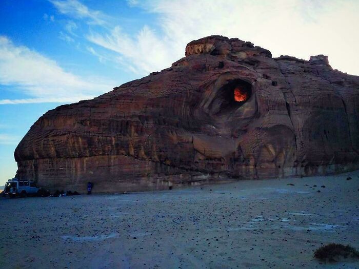 Formación rocosa sorprendente con una cavidad iluminada al atardecer, mostrando el poder de la naturaleza.
