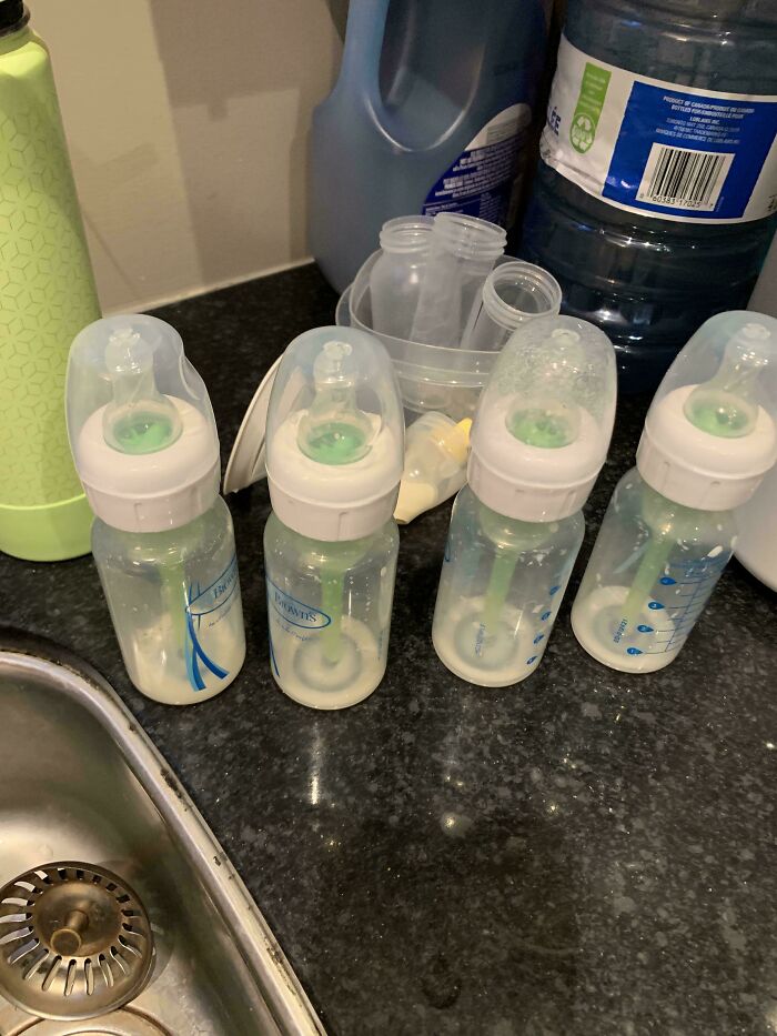 Biberones preparados por papá en momentos tiernos y divertidos de crianza junto a utensilios en cocina hogareña.