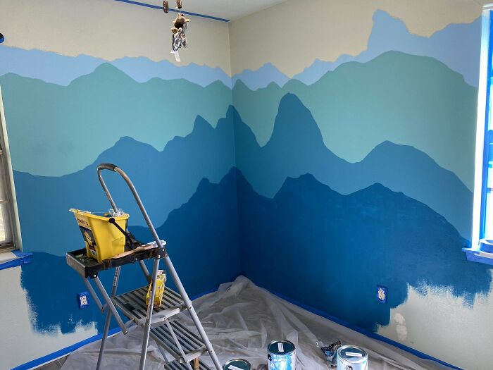 Pintura de habitaciones con montañas en varias tonalidades de azul, mostrando momentos divertidos de padres cuidando a sus hijos.
