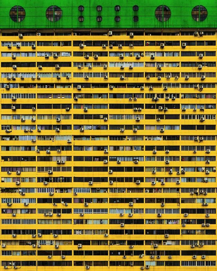 Edificio amarillo con numerosas unidades de aire acondicionado, representa el infierno urbano moderno.