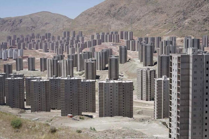 Vista de numerosos edificios altos de concreto en paisaje montañoso, ejemplo de infierno urbano.