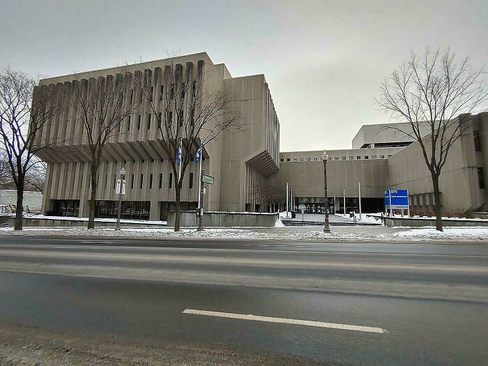 Edificio de hormigón en un entorno urbano frío, representando el infierno urbano, árboles sin hojas frente a él.