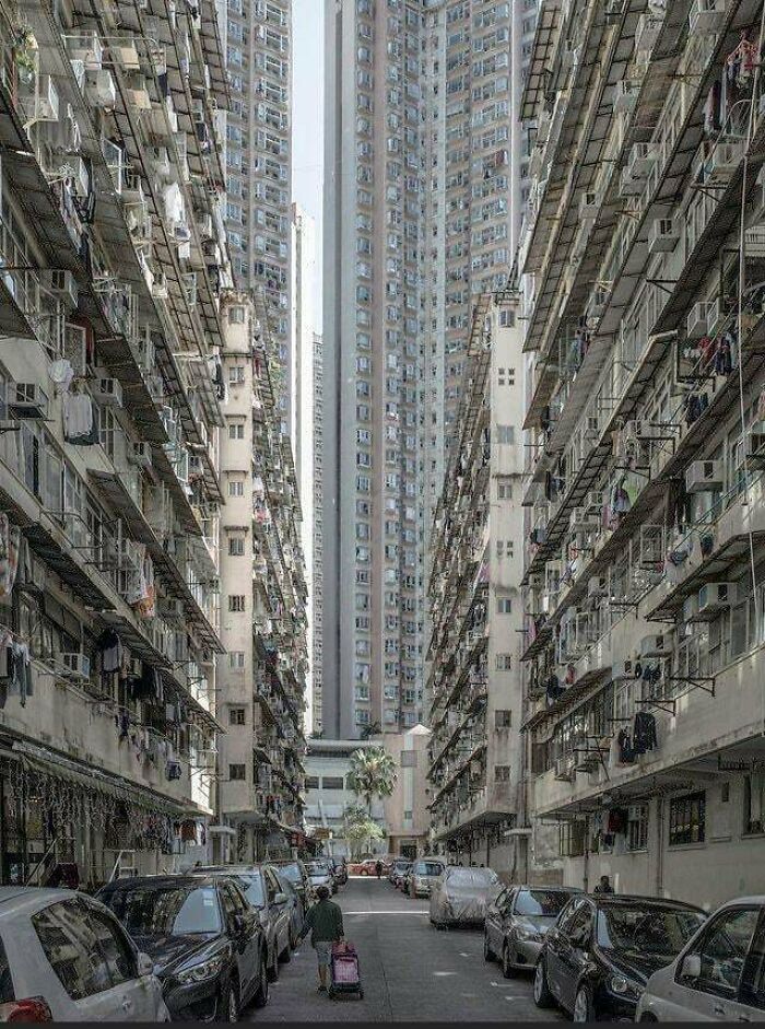 Calle estrecha rodeada de altos edificios urbanos, reflejando el infierno urbano construido por humanos.