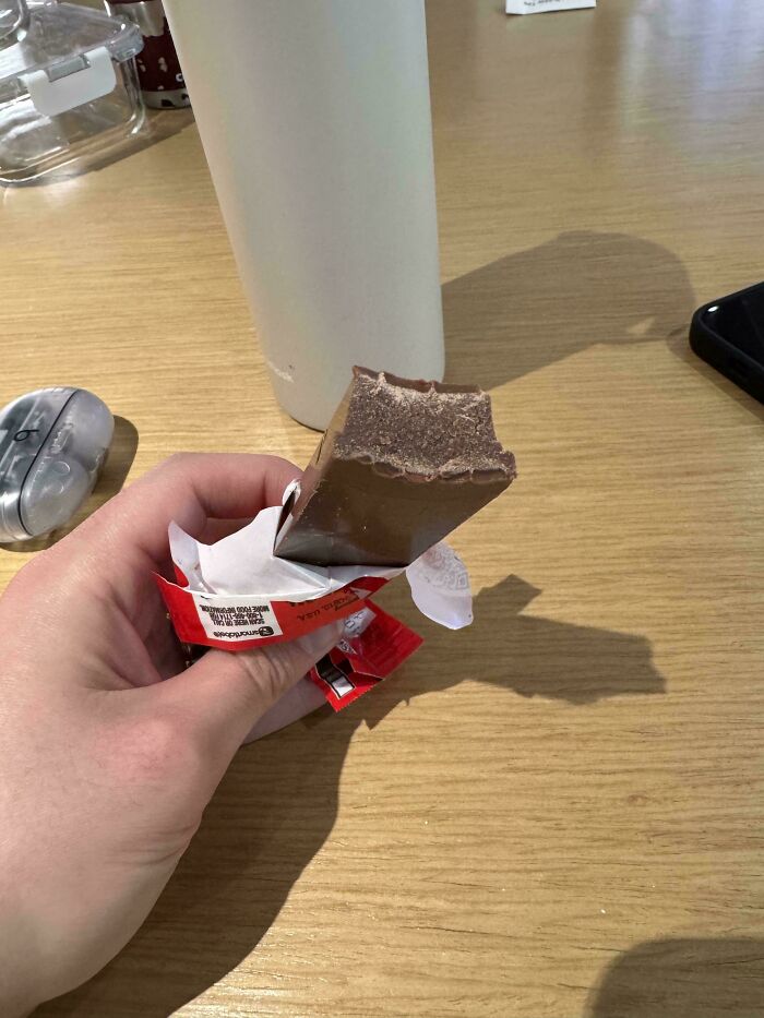 Persona sosteniendo una barra de chocolate mordida de forma irregular, ejemplo de fails que la gente documenta con humor.