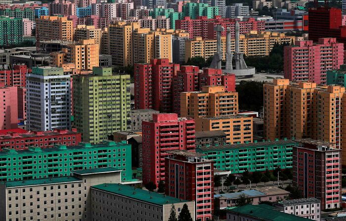 Bloques de edificios coloridos simbolizan el infierno urbano; arquitectura densa y opresiva.