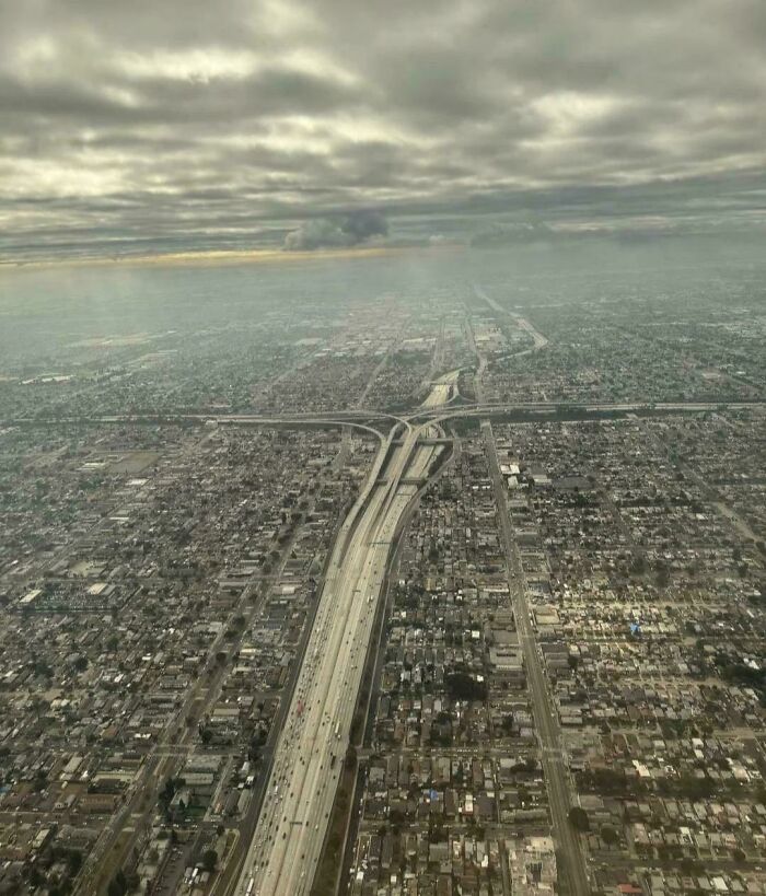 Vista aérea de una autopista rodeada de edificios bajo un cielo nublado, representando el infierno urbano.