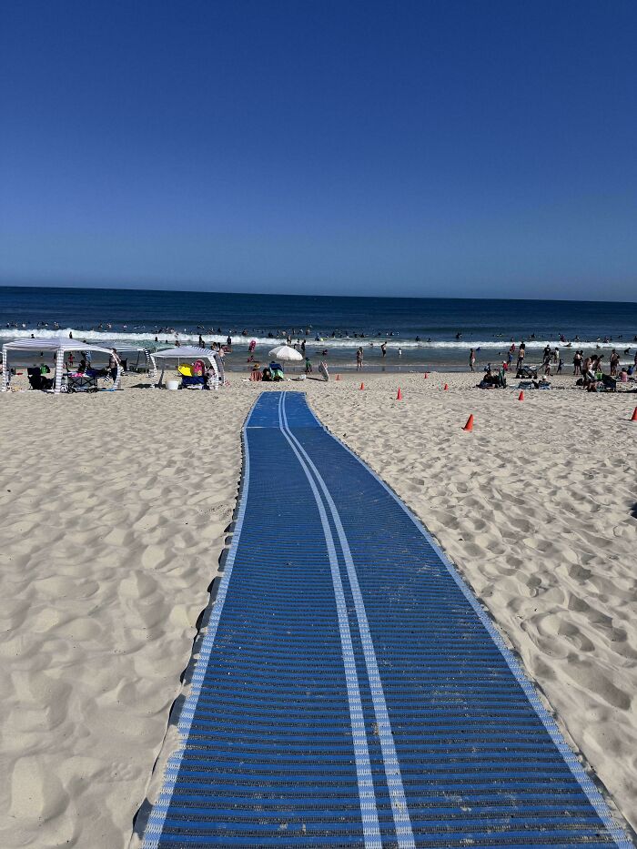 Camino de acceso a la playa en Australia con personas disfrutando del mar al fondo.