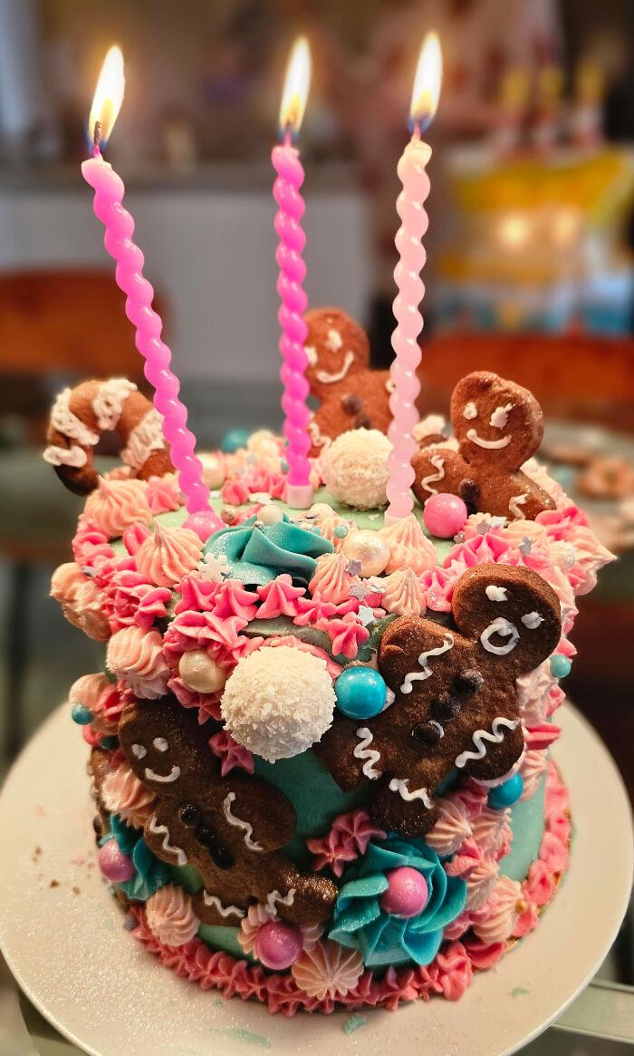 Pastel decorado con repostería creativa, galletas de jengibre y velas encendidas celebrando un evento especial.