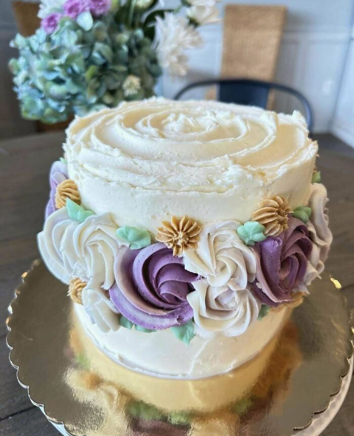 Pastel decorado con flores de betún en tonos morado y blanco, ejemplo destacado de repostería creativa y nivel avanzado.