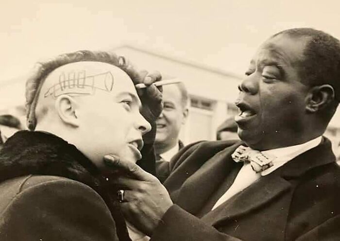 Louis Armstrong, trompetista estadounidense y uno de los artistas más influyentes de la historia del jazz, dibuja una trompeta y firma un autógrafo en la cabeza de un joven en Niza, Francia, 1961.