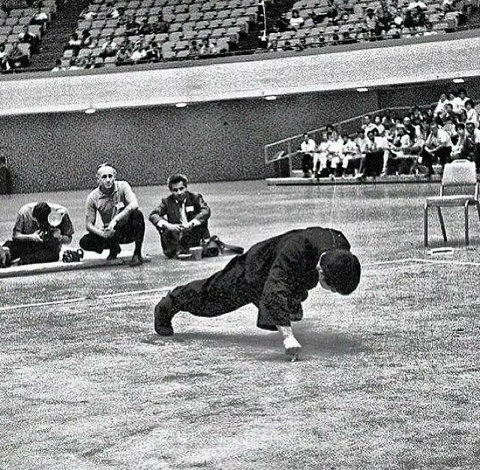 Bruce Lee en un ejercicio de flexiones con dos dedos y un brazo, años 70