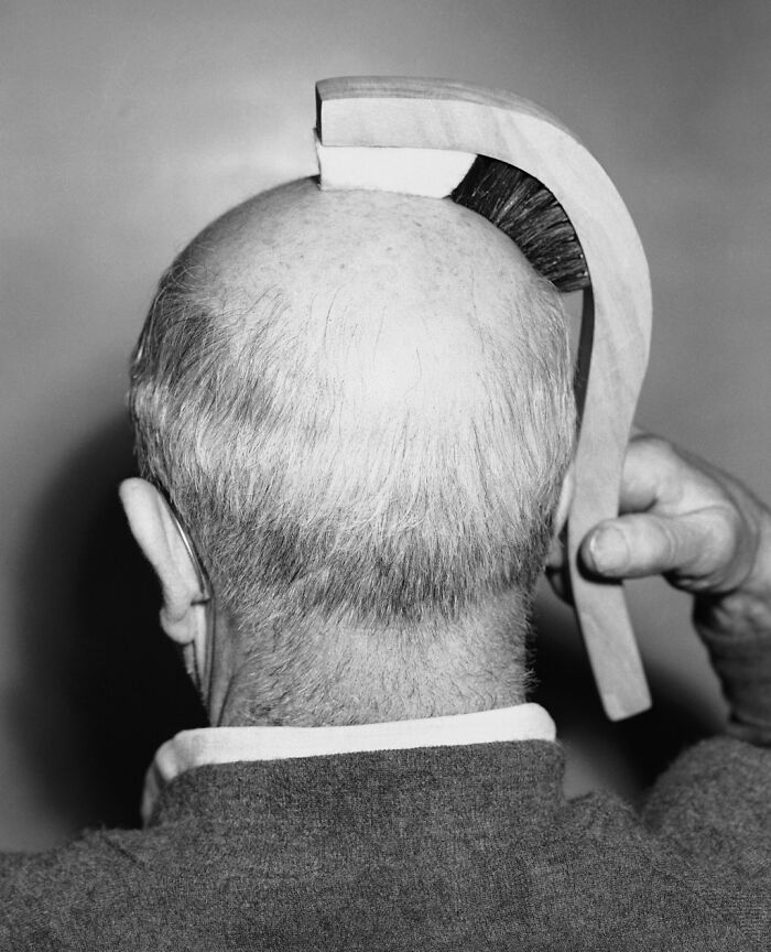  El Sr. Ted Spence, ingeniero de una empresa fabricante de cepillos de Los Ángeles, mostrando el nuevo “cepillo para la línea del cabello”, 12 de enero de 1950. El cepillo estaba construido para encajar en el contorno de una cabeza calva. Tenía cerdas para cepillar el cabello y una almohadilla de fieltro para masajear suavemente la cabeza calva