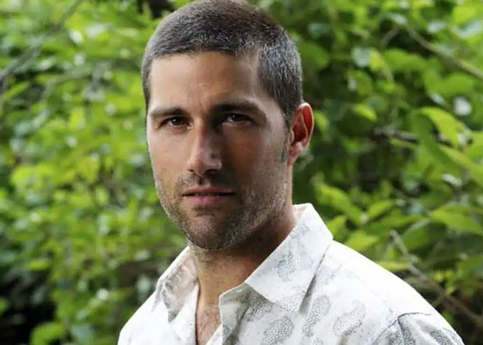 Hombre con camisa blanca, rostro serio, en exterior rodeado de vegetación, imagen relacionada con celebridades desaparecidas.