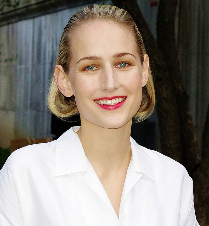 Mujer sonriendo con cabello rubio recogido, usando camisa blanca, ejemplo de celebridades que se desvanecieron poco a poco.