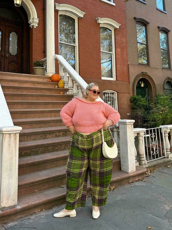 Persona posando con atuendo colorido frente a una townhouse, mostrando la realidad tras las fotos de Instagram.