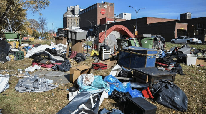 Campamento improvisado con basura y desorden en área urbana.