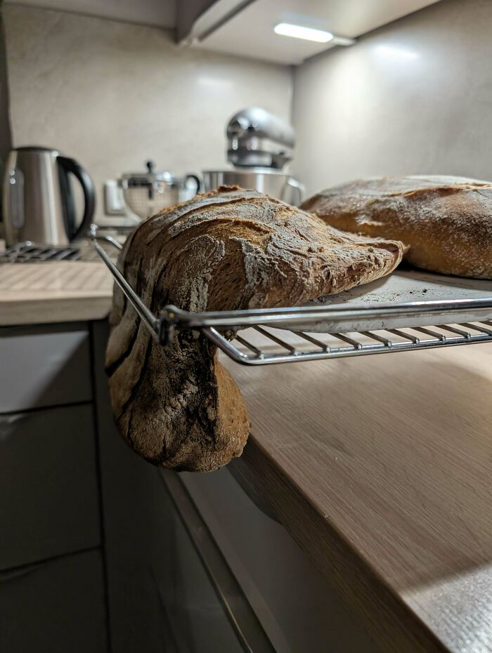 Pan artesanal con forma inusual enfriándose en la rejilla en una cocina moderna, llevándolo a otro nivel de repostería.
