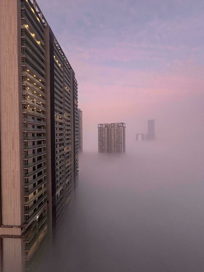 Edificios altos emergen entre la niebla, simbolizando el infierno urbano construido por los humanos.