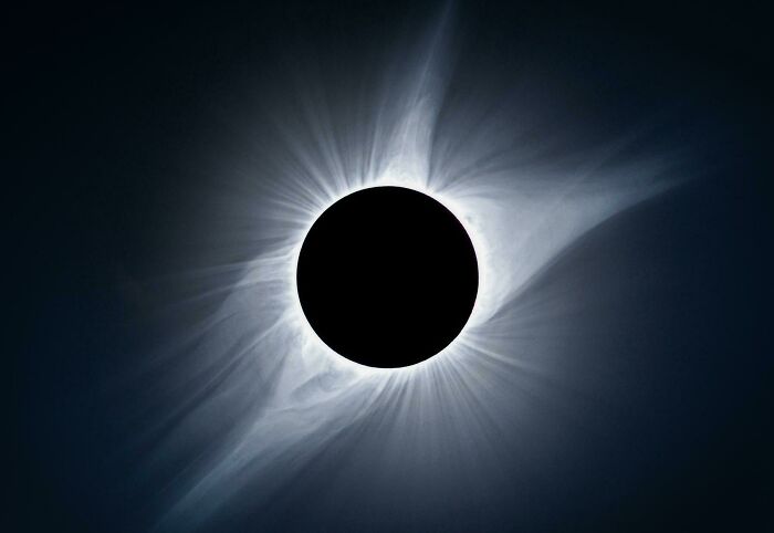 Eclipse solar total con halo brillante creando una imagen sorprendente con un toque de surrealismo en el cielo oscuro.