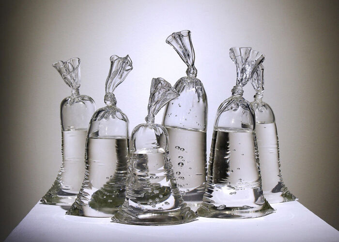 Bolsas de agua transparentes con burbujas formando una imagen sorprendente y surrealista en fondo neutro.