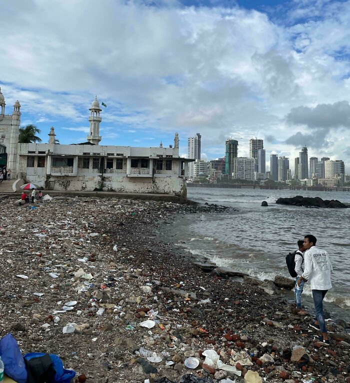 Playa en ciudad con basura y edificios, reflejando el «infierno urbano» construido por humanos.