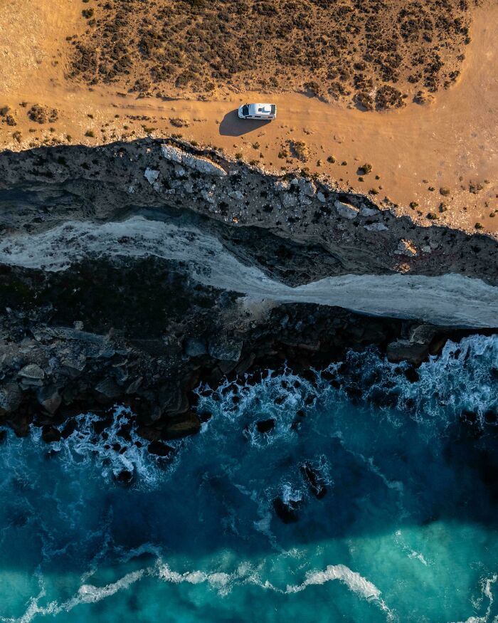 Vista aérea de un acantilado en Australia, con olas del océano y una camioneta en el borde.