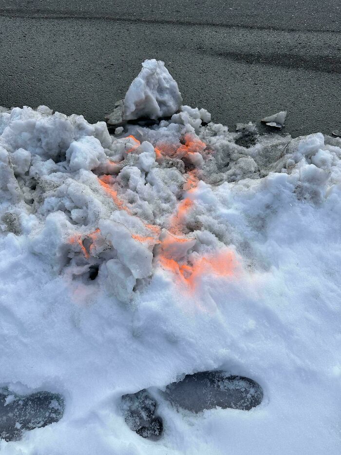 Nieve con marcas de pintura naranja mostrando trabajo de empleados perezosos.