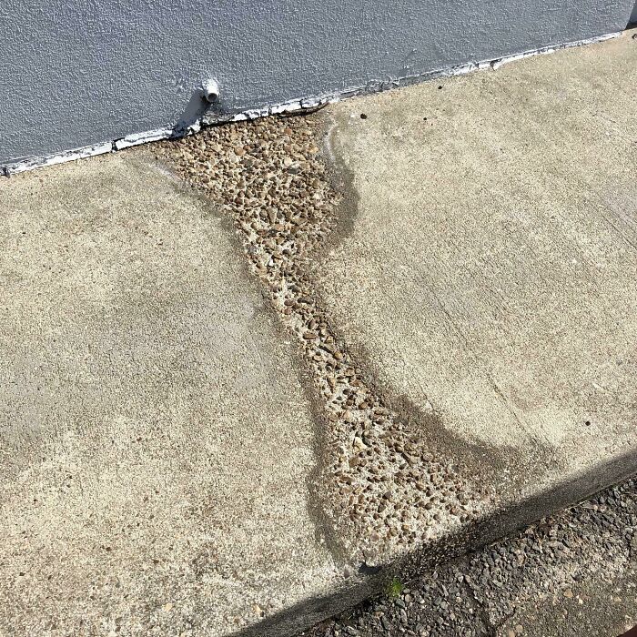 Años de flujo de agua de esta tubería de drenaje han desgastado este trozo de acera hasta la base rocosa.
