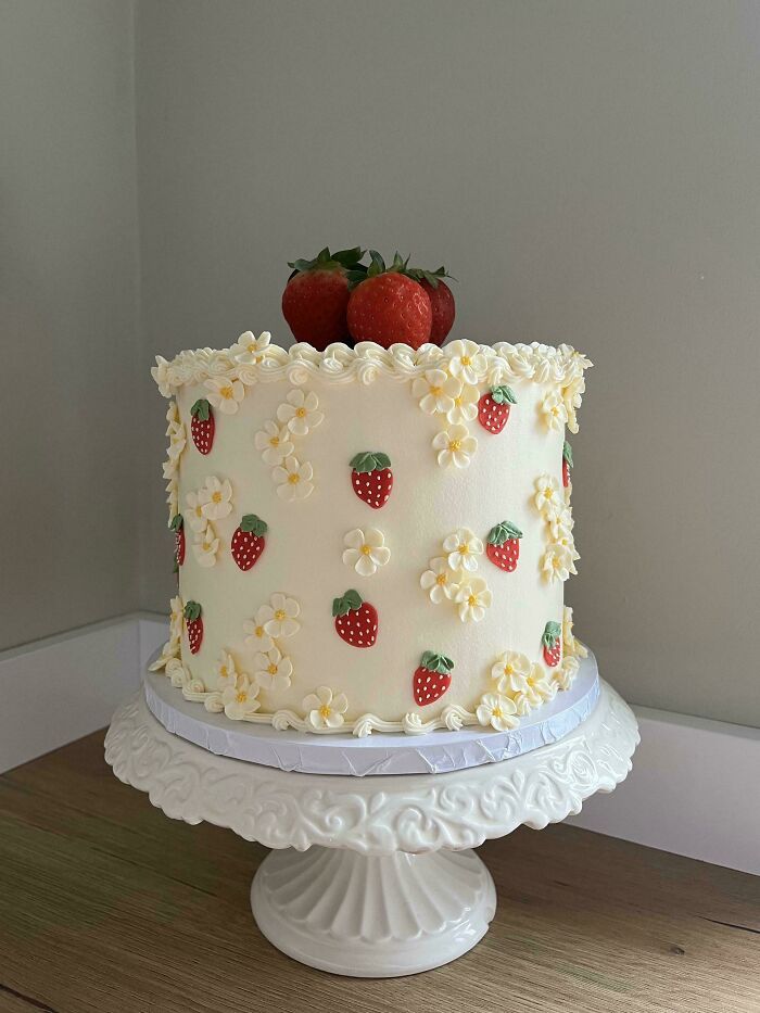 Pastel decorado con fresas y flores de crema, mostrando creatividad en repostería artesanal avanzada.