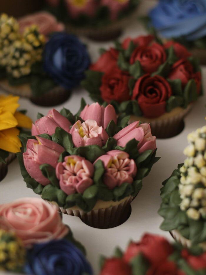 Cupcakes decorados con flores de crema, mostrando creatividad y técnica avanzada en repostería artesanal.