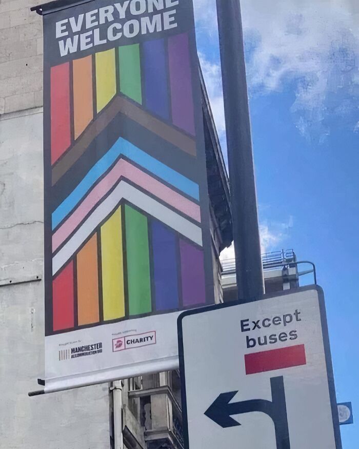 Cartel colorido con mensaje inclusivo y señal de tránsito en Reino Unido, reflejando humor británico fuera de contexto.