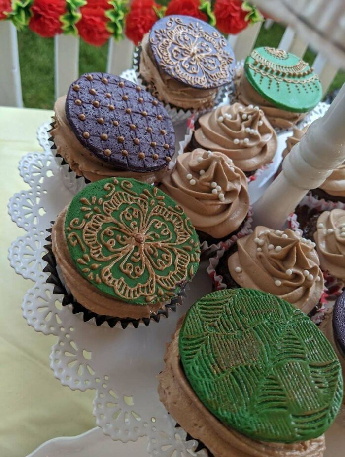 Cupcakes decorados con glaseado y detalles artísticos en colores verde y morado, ejemplo de repostería creativa.