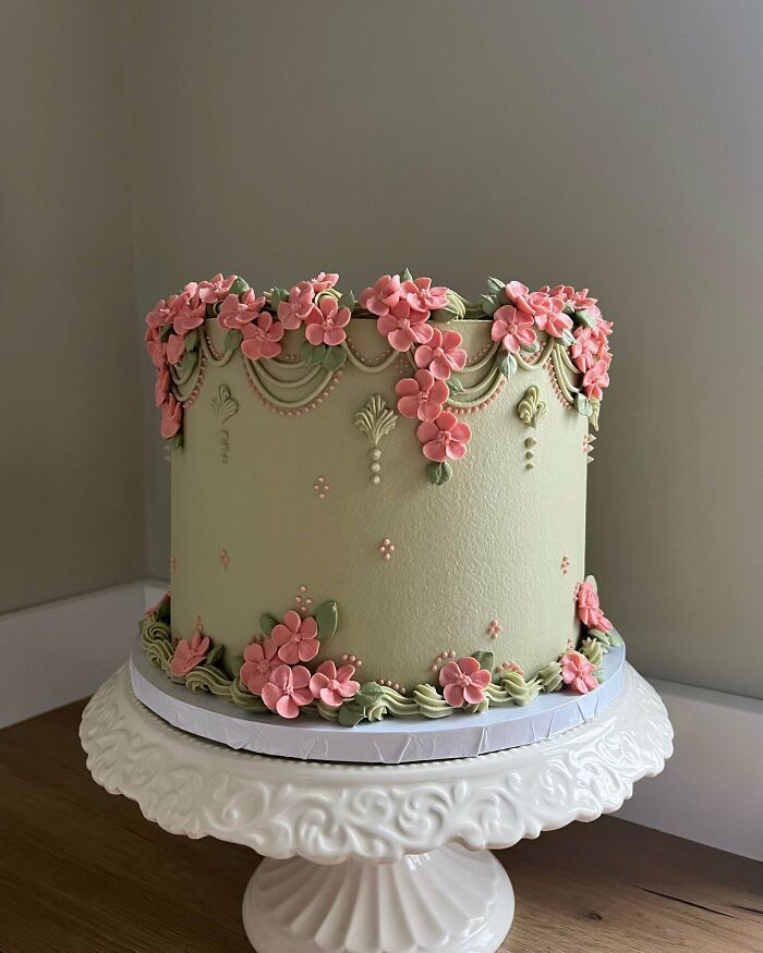 Pastel decorado con flores rosas y detalles verdes, mostrando repostería creativa y elegante llevada a otro nivel.