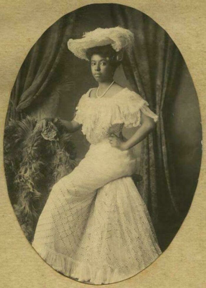 Retrato victoriano antiguo de mujer elegantemente vestida con vestido y sombrero, mostrando moda y estilo de la época victoriana.