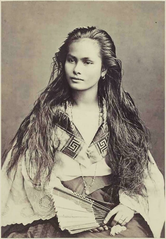 Joven con largo cabello y abanico, retrato en imagen histórica de la época victoriana mostrando tiempos muy distintos.