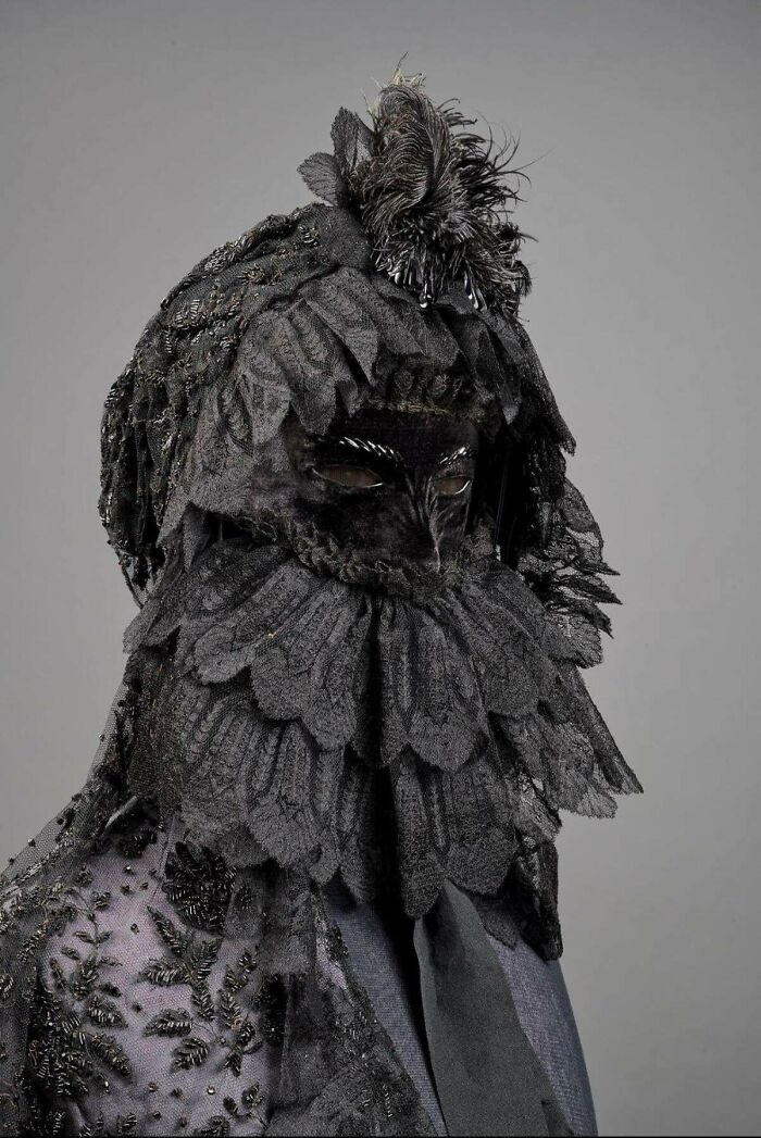 Máscara victoriana negra con detalles en encaje y plumas, representando la época victoriana y su moda distintiva.