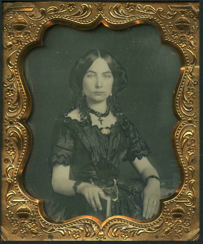 Retrato victoriano de mujer con vestimenta y joyas típicas de la época victoriana en marco decorativo antiguo.