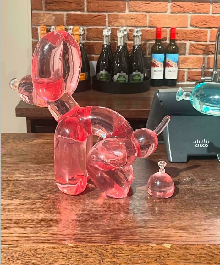 Escultura de globo de perro rosa transparente en mesa de madera, ejemplo de personas con buenas habilidades para sus ideas.