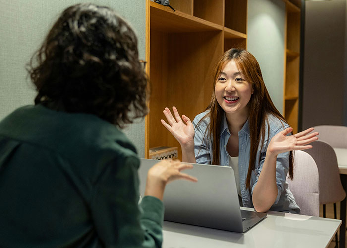 Mujeres conversando en oficina con laptop, compartiendo códigos de trucos para el juego de la vida exitosamente.