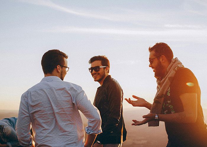 Tres hombres conversando al atardecer aplicando códigos de trucos para el juego de la vida y disfrutar el momento.