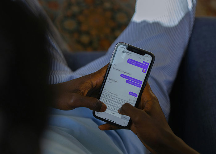 Persona usando un teléfono móvil, leyendo mensajes y buscando códigos de trucos para el juego de la vida.