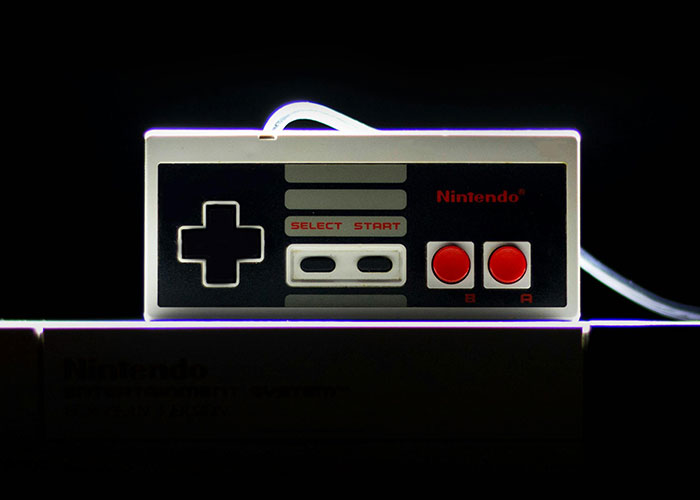 Control clásico de Nintendo con botones rojos, representando códigos de trucos para el juego de la vida en modo retro.