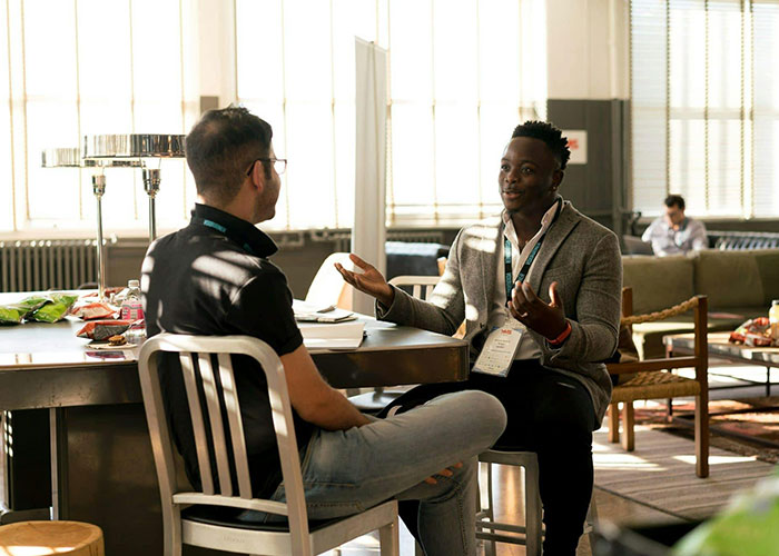 Dos personas conversando en un espacio moderno sobre códigos de trucos para el juego de la vida exitosos.